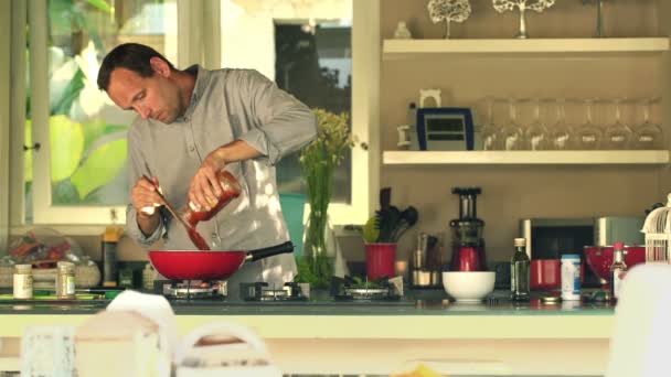 Hombre cocinar y verter salsa en la cocina — Vídeos de Stock