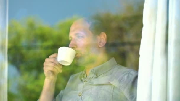 Hombre disfrutando del café de la mañana junto a la ventana — Vídeo de stock