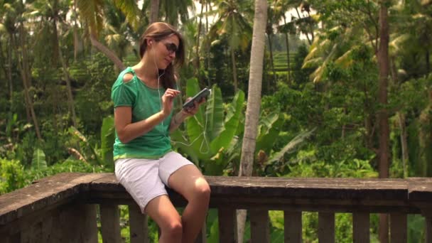 Vrouw luisteren naar muziek op smartphone op terras — Stockvideo
