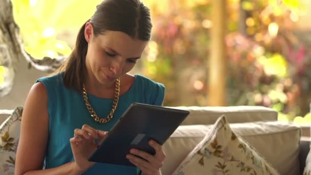 Vrouw zitten met tablet op de sofa thuis — Stockvideo