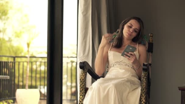 Frau textet auf Smartphone auf Schaukelstuhl — Stockvideo