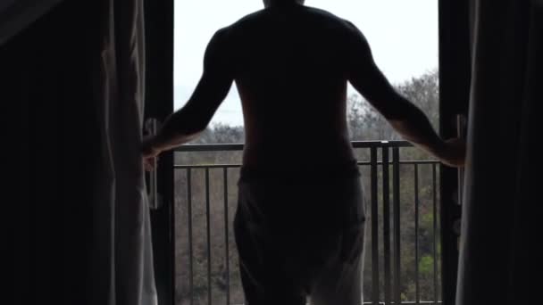 El hombre desvela cortinas, disfrutando de la mañana junto a la ventana — Vídeos de Stock