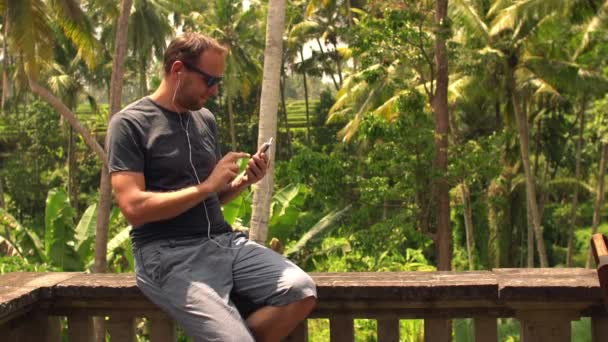 Man, luisteren naar muziek op smartphone op terras — Stockvideo