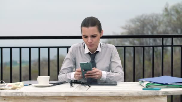 Businesswoman texting on smartphone by the table — Stock Video