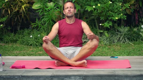 Homem meditando no tapete no jardim — Vídeo de Stock