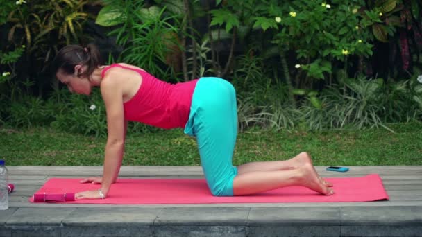 Femme faisant chat chameau exercice sur tapis dans le jardin — Video