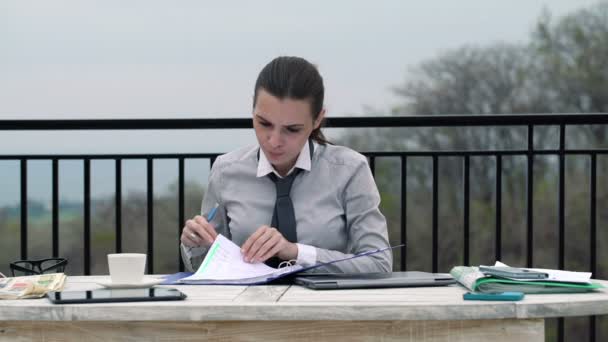 Empresaria escribiendo notas en documentos en terraza — Vídeos de Stock