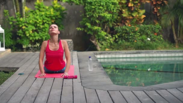 Žena, která dělá jógu pozice na rohoži v zahradě — Stock video