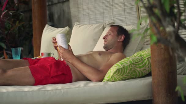 Homem lendo livros na cama gazebo — Vídeo de Stock