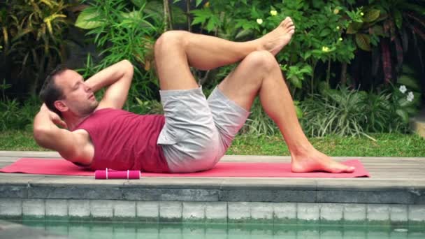 Hombre haciendo giros abdominales en la estera en el jardín — Vídeo de stock