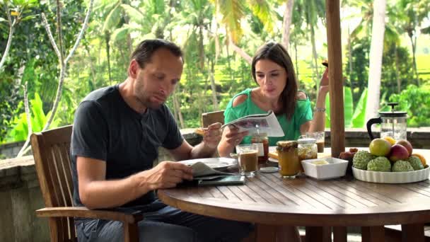 Couple eating and reading newspaper on terrace — Stock Video