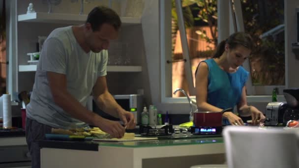 Pareja preparando la comida en la cocina por la noche — Vídeos de Stock