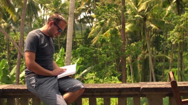 Attractive man reading book on terrace — Stock Video