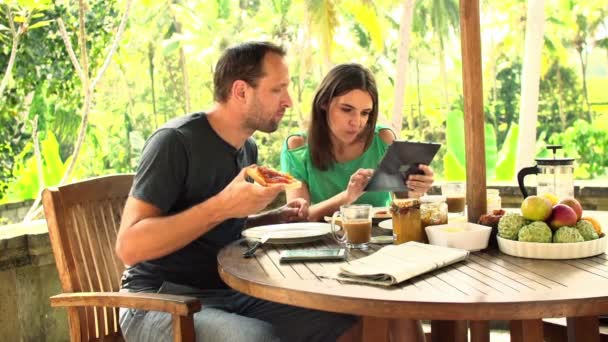 Par med hjälp av tablet PC, prata och äta — Stockvideo