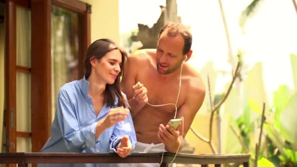 Пара слушает музыку на мобильном телефоне на террасе — стоковое видео
