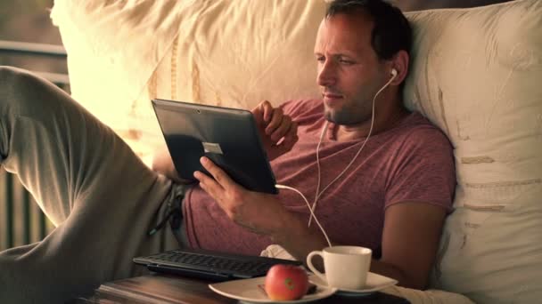 Чоловік дивиться фільм на планшетному комп'ютері — стокове відео