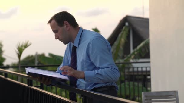 Hombre de negocios leyendo documentos en la terraza — Vídeos de Stock