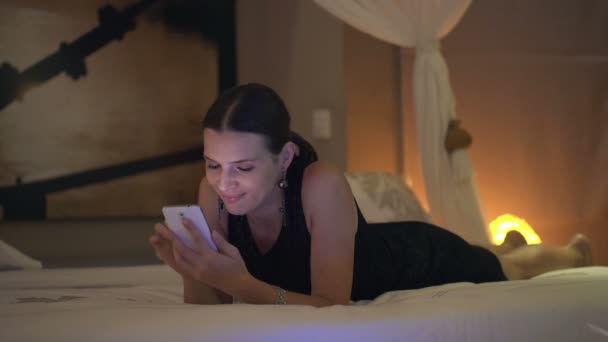 Kvinna med hjälp av smartphone på sängen — Stockvideo