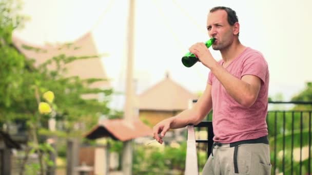 Hombre beber cerveza y fumar cigarrillo en la terraza — Vídeos de Stock