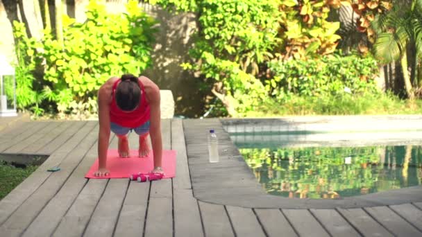 Vrouw doen plank oefening op mat in de tuin — Stockvideo