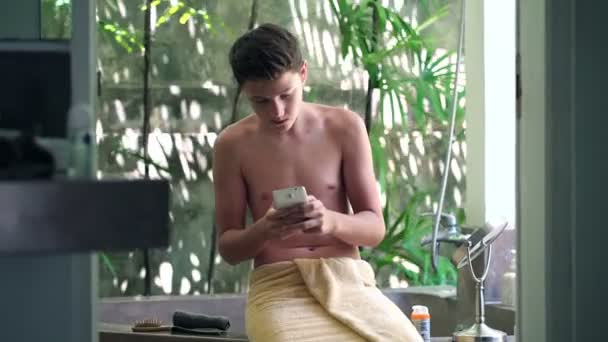 Teenager texting on smartphone in bathroom — Stock Video