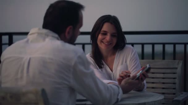 Couple watching photos on smartphone on terrace — Stock Video