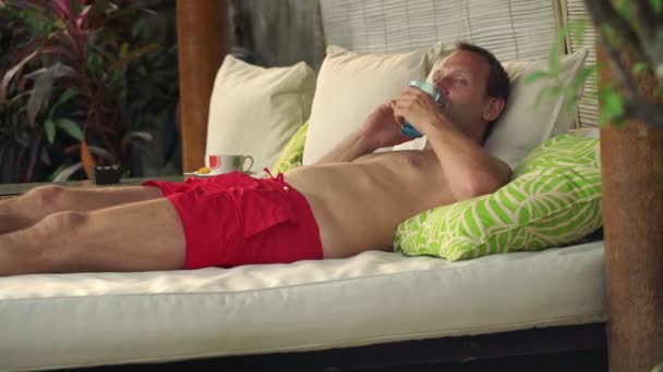 Чоловік говорить на мобільному телефоні на альтанці ліжко — стокове відео