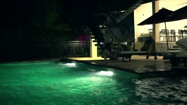 Adolescente pulando na piscina à noite — Vídeo de Stock
