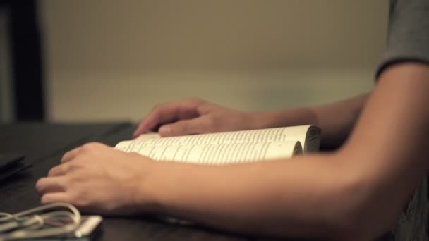 Teenager reading book by the table at night — Stock Video