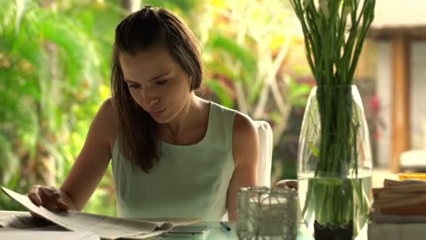 年轻女实业家看广告报纸在家里的餐桌 — 图库视频影像