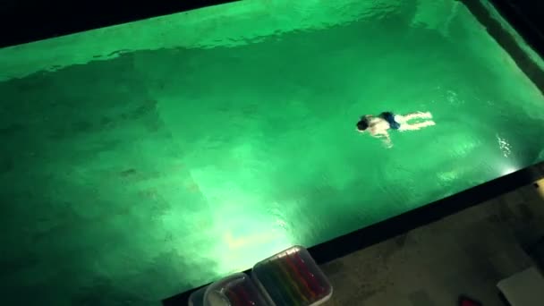 Boy swimming in the swimming pool at night — Stock Video