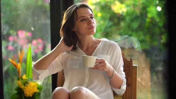 Zamyšlená žena pít čaj na židli — Stock video