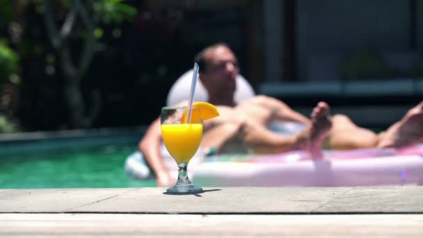 Мужчина расслабляется на надувном матрасе в бассейне — стоковое видео