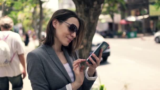 Business woman with smartphone standing by street in city — стоковое видео