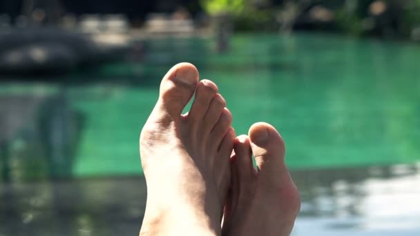 Pieds masculins sur une banquette près de la piscine — Video