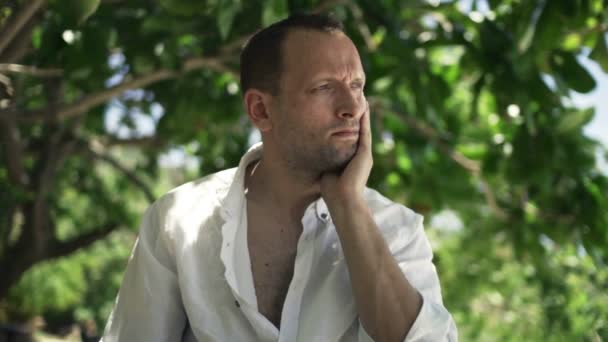 Trauriger, unglücklicher Mann sitzt im Park — Stockvideo