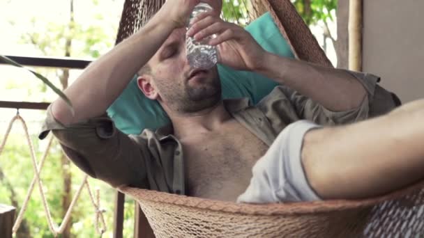 Человек охлаждается водой на гамаке — стоковое видео