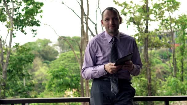 Tablet bilgisayarda teras ile başarılı iş adamı — Stok video