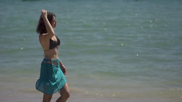 Giovane donna in pareo a piedi sulla spiaggia — Video Stock