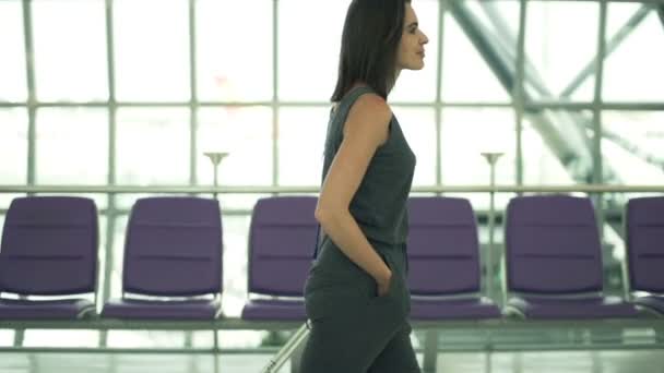 Ung kvinna med resväska promenader på flygplats — Stockvideo