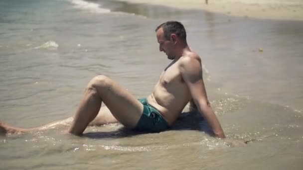 Handsome man relaxing and sunbathing on beach — Stock Video