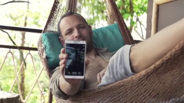 Muž s selfie foto s mobil na houpací síť — Stock video
