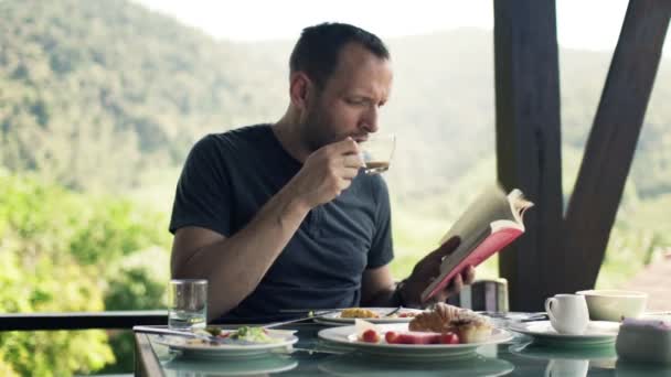 Hombre leyendo libro y bebiendo café — Vídeos de Stock