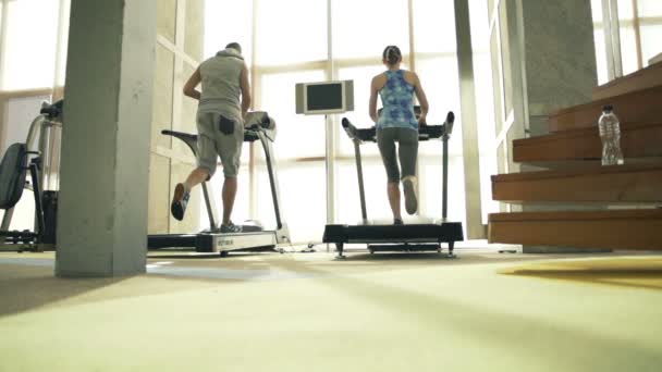 Mensen lopen, lopen op de loopband in de sportschool — Stockvideo