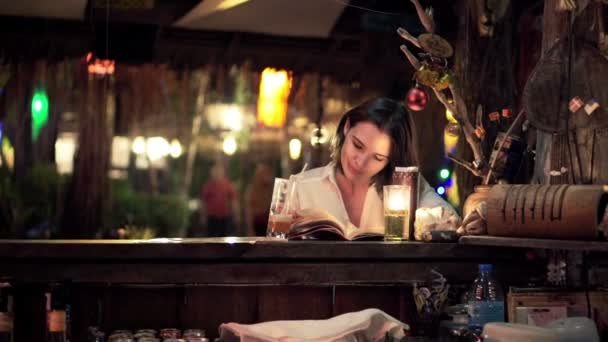 Mujer leyendo libro y bebiendo cóctel en la cafetería — Vídeos de Stock