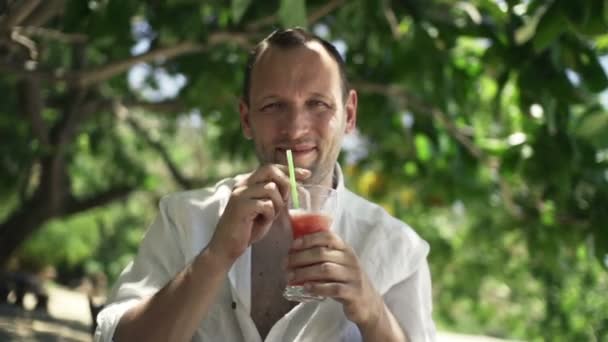Muž, zvyšování přípitek a pít koktejl v parku — Stock video
