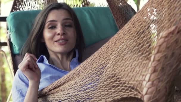 Kobieta mówi do kamery leżącego na hamaku — Wideo stockowe