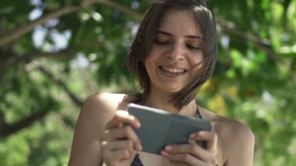 Vrouw speelspel op smartphone in park — Stockvideo