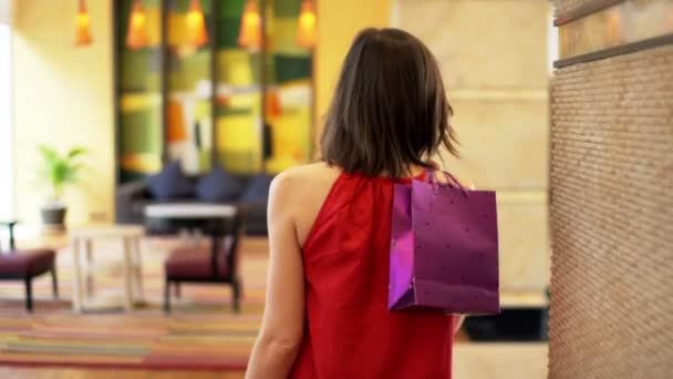 Mujer con bolsa de compras caminando por el pasillo del hotel — Vídeo de stock