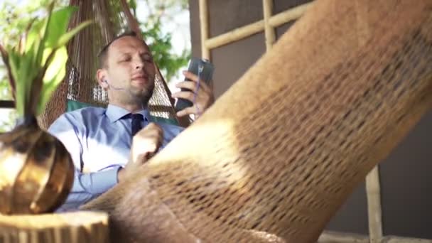 Hombre de negocios escuchando música y cantando en hamaca — Vídeo de stock